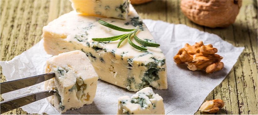 Stilton cheese on wood board with nuts.